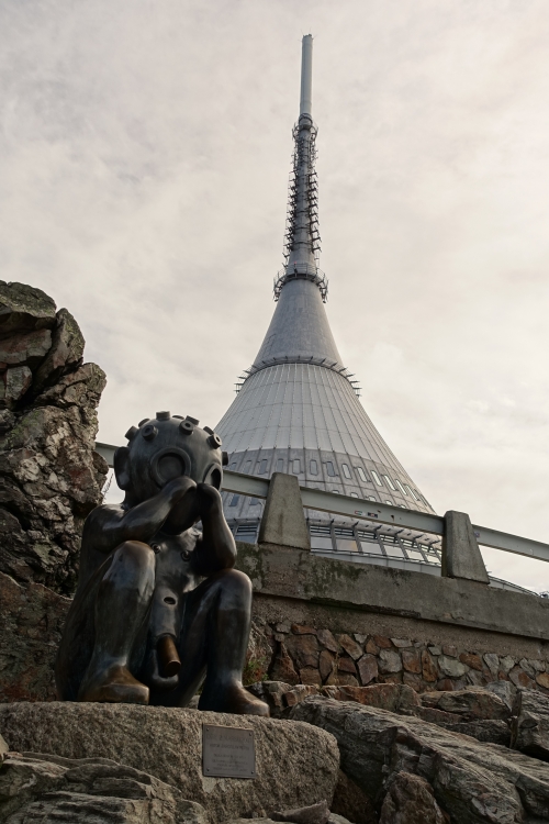 Bronzener weinender Alien vor raumschiffartigem Gebäude