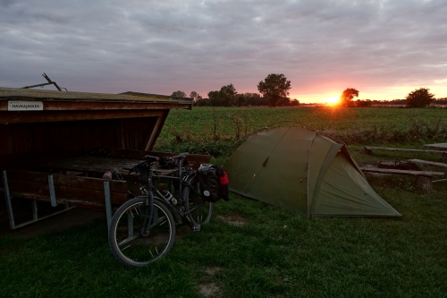 Zelt und Fahrrad vor rotem Sonnenuntergang
